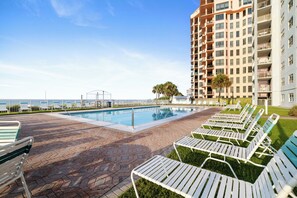 A swimming pool with lounge chairs and a high-rise building in the background. - Sunswept 602 by Liquid Life (Orange Beach)