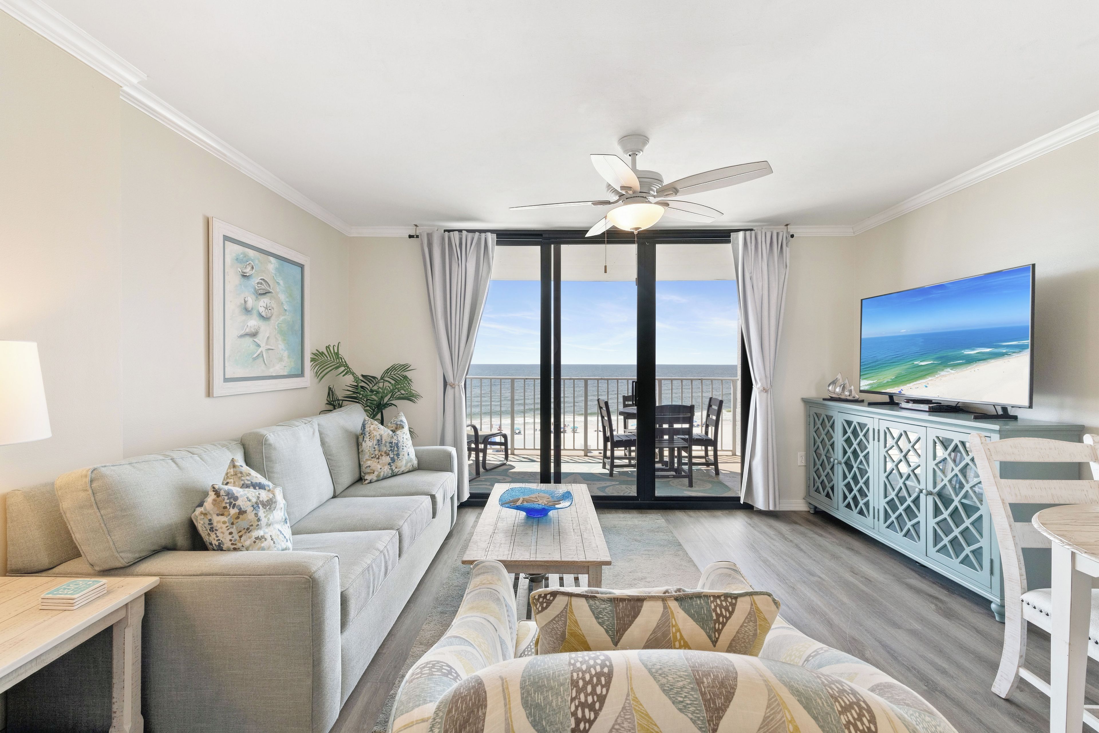 Un salon comprenant un canapé, une table basse, un téléviseur et un balcon avec vue sur l’océan.