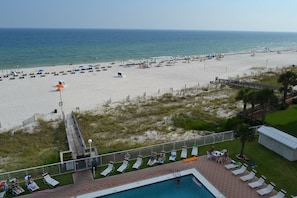 Ein Strand mit Poolbereich, Liegestühlen und Sonnenschirmen.