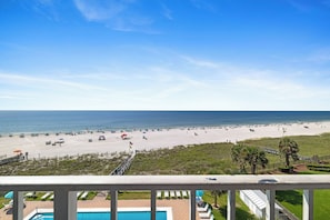 Een strand met parasols en ligbedden, een zwembad en uitzicht op de oceaan.