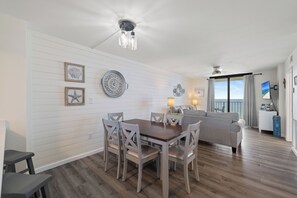 A dining area with a wooden table and chairs, a ceiling fan, and wall-mounted decorative plates. - Sunswept 607 by Liquid Life (Orange Beach)