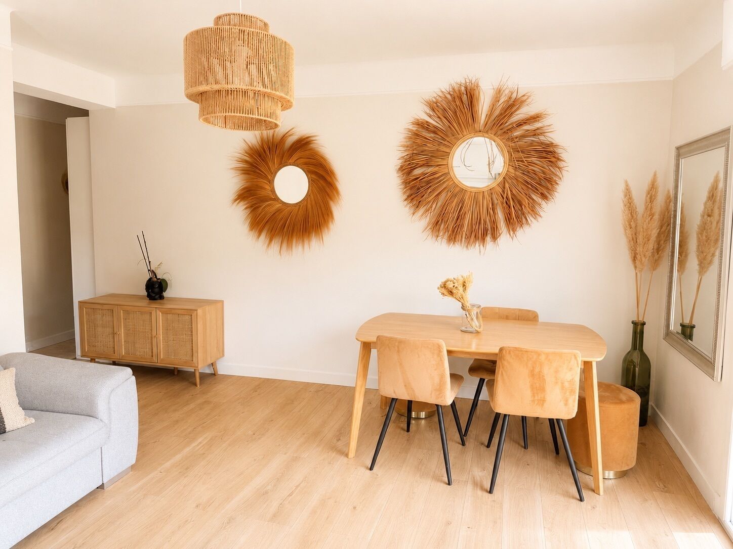 A modern living room with a dining table, two round wall decorations, a hanging light fixture, a sofa, and a cabinet.