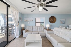 A room with a ceiling fan, a sofa, a coffee table, and a window with blinds. - Sunswept 608 by Liquid Life (Orange Beach)