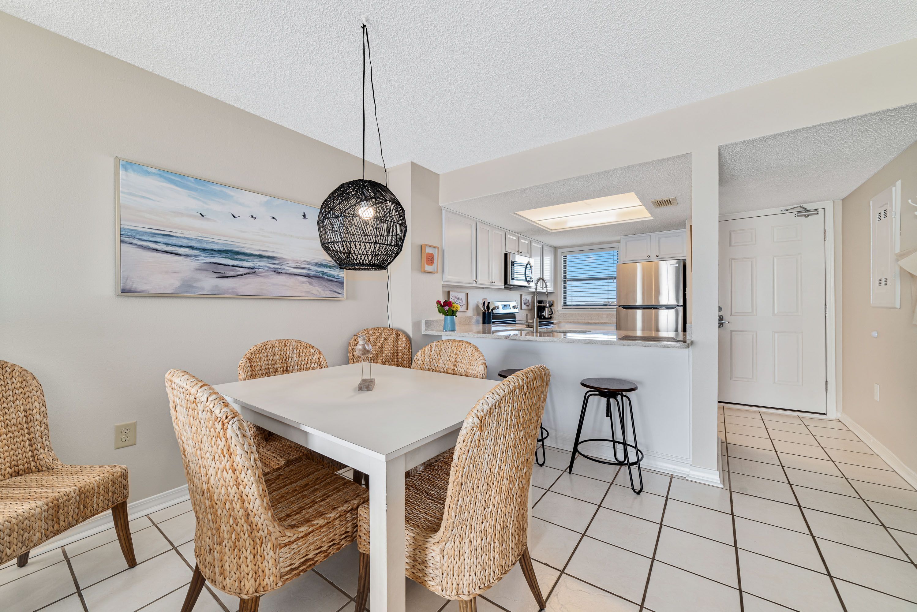 A modern kitchen with white cabinetry, stainless steel appliances, and a breakfast bar.