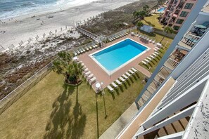 Ein Poolbereich mit rechteckigem Pool, umgeben von Liegestühlen und einem kleinen Garten.