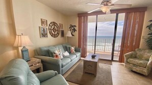 A living room with a sofa, a coffee table, a lamp, and a view of the ocean through large windows. - Sunswept 704 by Liquid Life (Orange Beach)