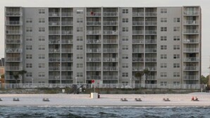 A multi-story hotel with balconies, located near a beach with boats. - Sunswept 704 by Liquid Life (Orange Beach)