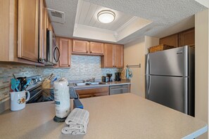 Une cuisine moderne avec des meubles en bois, un réfrigérateur en acier inoxydable et un dosseret carrelé.