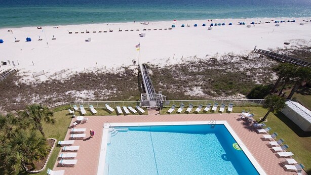 A pool area with a rectangular pool, surrounded by lounge chairs and a deck. - Sunswept 704 by Liquid Life (Orange Beach)