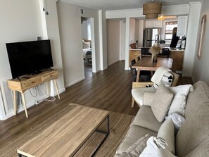 Ein modernes Wohnzimmer mit Flachbildfernseher, Couchtisch aus Holz und einer Couch.
