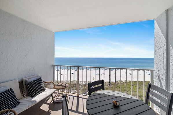 Un balcón con vista a la playa, una mesa y un sofá.