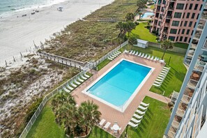 Ein Resort mit Swimmingpool, Liegestühlen, Strand und einem Gebäude mit Balkonen.
