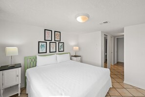 Ein Hotelzimmer mit einem großen Bett, zwei Nachttischen, einer Stehlampe und gerahmten Bildern an der Wand.