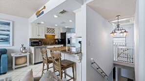 Une cuisine moderne avec des meubles blancs, des appareils en acier inoxydable et un coin repas doté de chaises en bois.