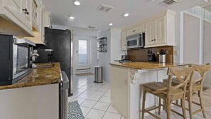 A modern kitchen with a central island, a microwave, and a stove. - Sunswept 804 by Liquid Life (Orange Beach)