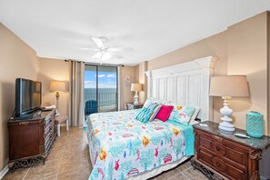 A hotel room with a bed, a television, a desk, and a view of the ocean. - Sunswept 806 Penthouse by Liquid Life (Orange Beach)