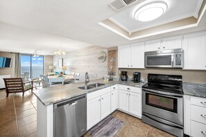Una cocina moderna con electrodomésticos de acero inoxidable, armarios blancos y vistas al exterior.