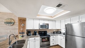 Eine moderne Küche mit weißen Schränken, Edelstahlgeräten, einer eingebauten Mikrowelle und einem großen Kühlschrank.