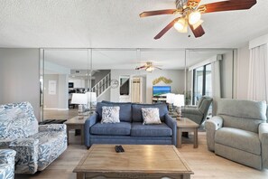 Ein modernes Wohnzimmer mit einem blauen Sofa, einem grauen Sessel und einem Holztisch.