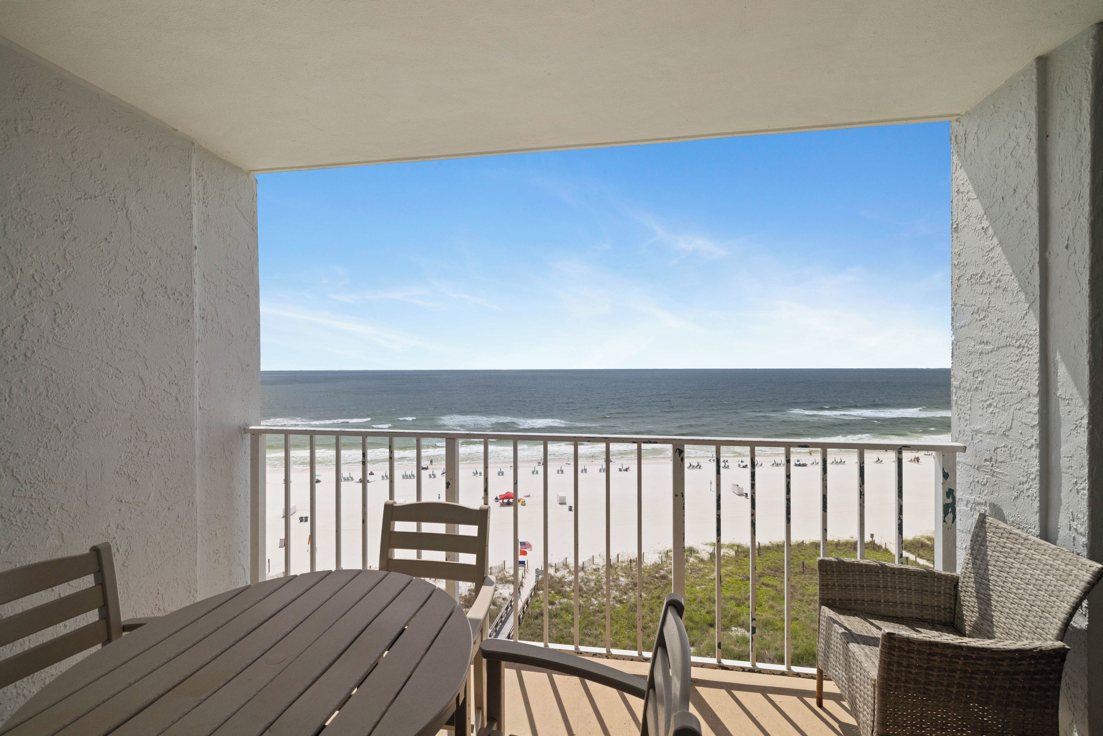 Een balkon met uitzicht op strand en zee.