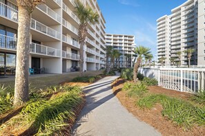 A modern hotel with multiple floors, outdoor seating, and palm trees. - Seaside Beach & Racquet 4612 by Liquid Life (Orange Beach)