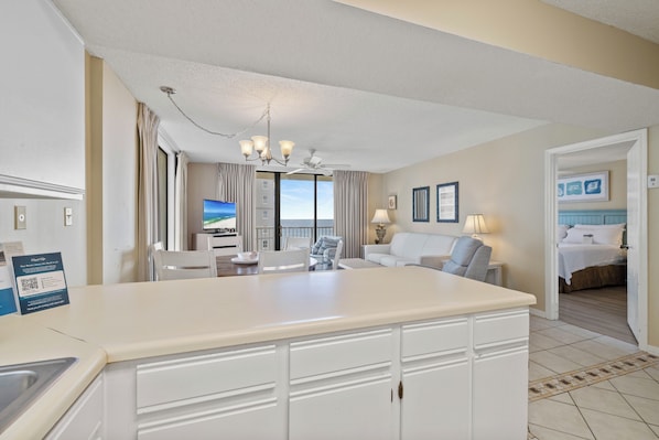 A hotel room with a dining area, a large window with a view, a chandelier, and a bed. - Seaside Beach & Racquet 4612 by Liquid Life (Orange Beach)