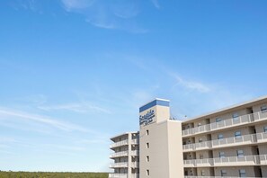 Ein mehrstöckiges Hotel mit Balkonen, einem Schild mit der Aufschrift 'Seaside Resort Hotel' und einem strahlend blauen Himmel.