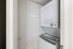 Ein Waschraum mit einer Waschmaschine und einem Trockner, einer Tür und einer an der Wand montierten Steuerung.