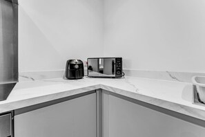 A kitchen with a built-in microwave and coffee maker on a marble countertop. - Spacious & Modern Anfield Flat | WiFi | Sleeps 4 (Anfield)