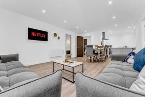 Ein modernes Wohnzimmer mit grauen Sofas, einem Couchtisch und einem flachbildfernseher an der Wand.