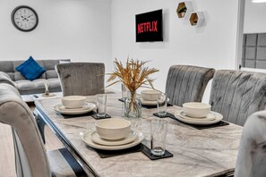 A dining area with a marble table set for four, surrounded by grey upholstered chairs. - Spacious & Modern Anfield Flat | WiFi | Sleeps 4 (Anfield)