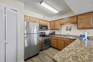 Eine Küche mit Holzschränken, Edelstahlgeräten, einer Arbeitsplatte aus Granit und einem Gemälde an der Wand.