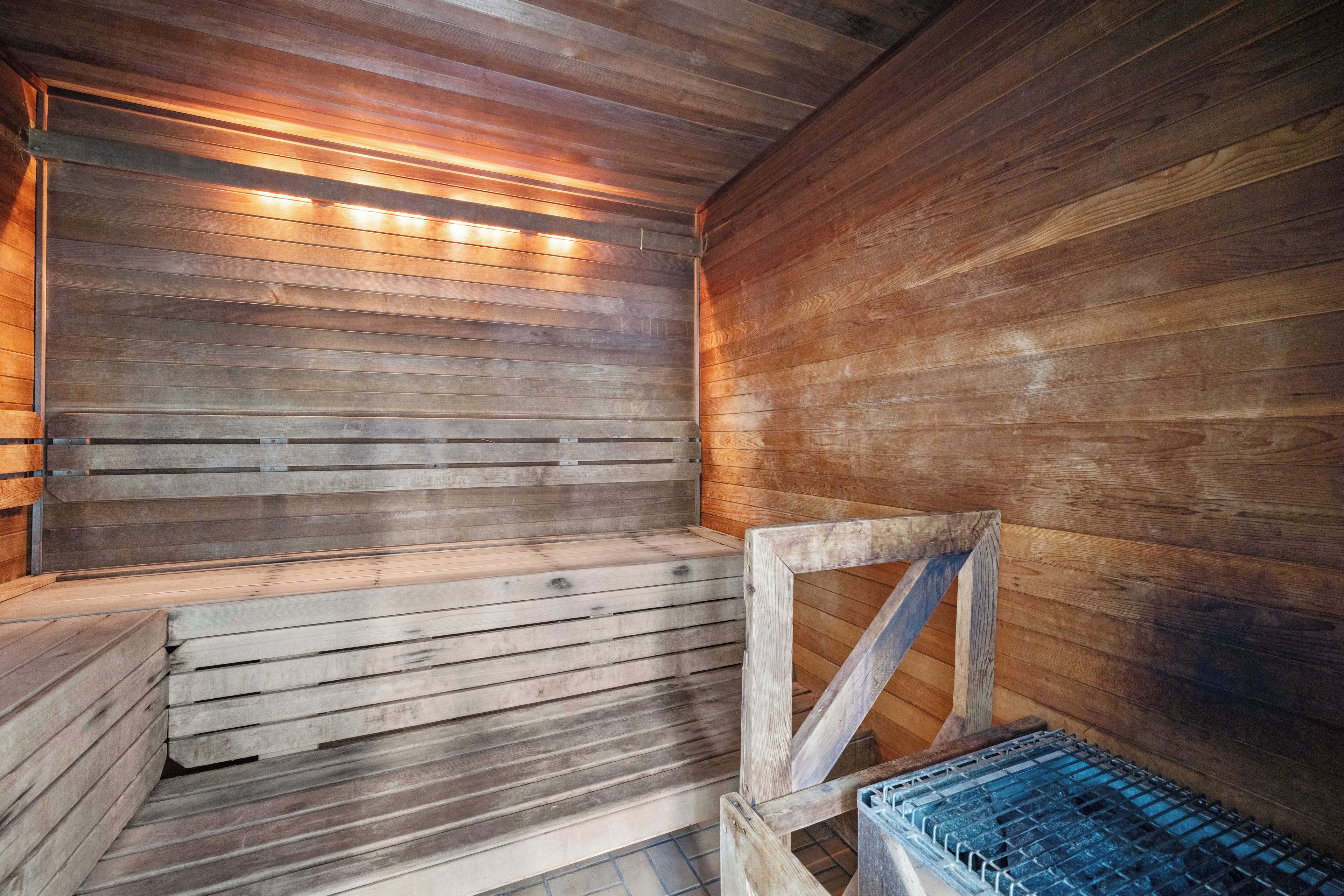 Un sauna avec des murs et des bancs en bois, un banc en métal et un élément décoratif aquatique bleu.