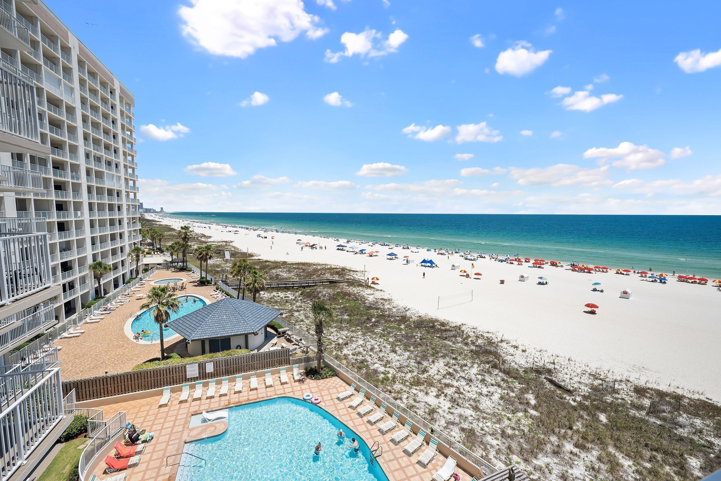 A hotel with a pool, beach, and ocean view.
