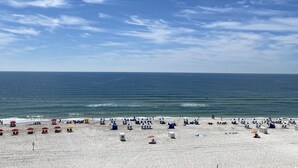 A beach with numerous umbrellas and sun loungers, a clear sky, and the ocean in the background. - Shoalwater 604 by Liquid Life (Orange Beach)