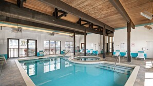 An indoor swimming pool with clear water, surrounded by lounge chairs and a wooden ceiling structure. - Shoalwater 604 by Liquid Life (Orange Beach)