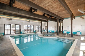 An indoor swimming pool with clear water, surrounded by lounge chairs and a wooden ceiling structure. - Shoalwater 604 by Liquid Life (Orange Beach)