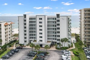 Ein mehrstöckiges Hotel mit Balkonen, einem Parkplatz und Blick auf den Strand.