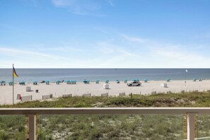 A beach with umbrellas, chairs, and a flag. - Silver Beach 203 by Liquid Life (Orange Beach)