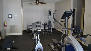 Uma academia com equipamentos de cardio, máquinas de peso e halteres.