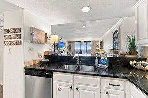 Cocina moderna con lavavajillas, doble pileta y vista al área de estar.