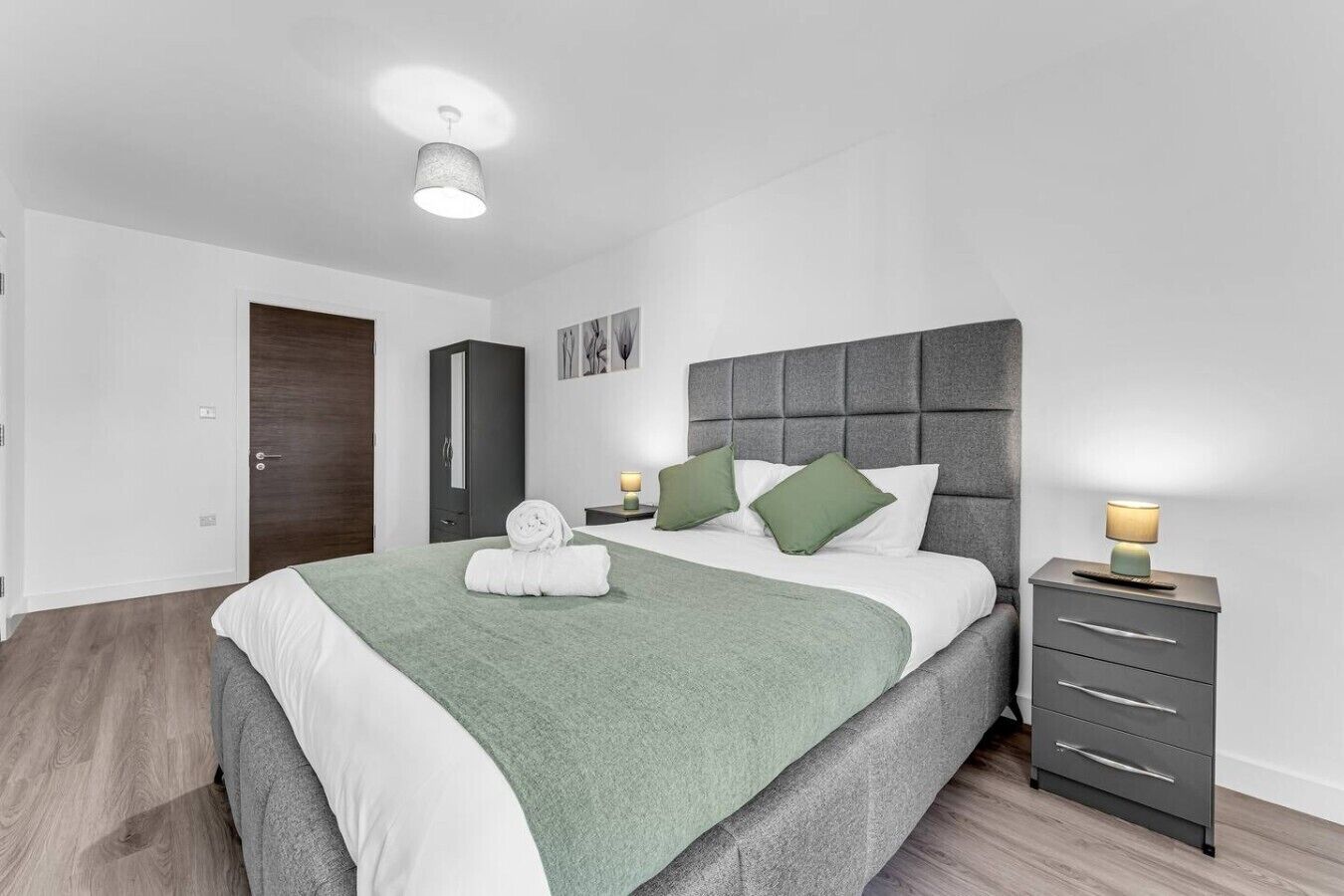 Ein modernes Schlafzimmer mit Bett, Nachttischen, einem Kleiderschrank und einer Deckenleuchte.