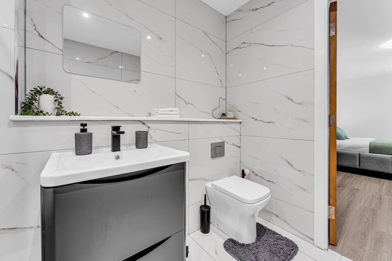 Ein modernes Badezimmer mit einem weißen Marmorwaschbecken, einer Toilette und einer Duschkabine.