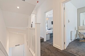 A hallway leading to a bedroom with a bed, a radiator, and a chair. - Spacious 5BR House in Staveley | Wi-fi | Sleeps 10 (Staveley)