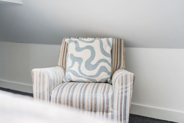 A striped armchair with a patterned cushion against a plain wall.