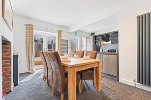 A modern kitchen with a built-in oven and a dining area with a wooden table and leather chairs. - Spacious 5BR House in Staveley | Wi-fi | Sleeps 10 (Staveley)