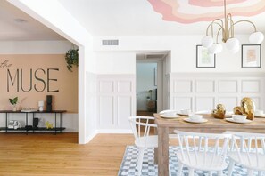 A dining area with a wooden table, white chairs, and a checkered rug.