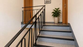 Una escalera con barandilla de metal, una planta en maceta y un cuadro en la pared.
