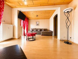 Ein Wohnzimmer mit einer Couch, einem roten Tisch, einer Stehlampe und einer Heizung.