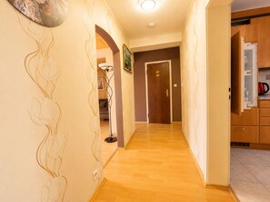 A hallway with wooden flooring, a door with a handle, and a kitchen area with cabinets and a red kettle. - Time out Above the Rooftops of Boppard (Boppard)